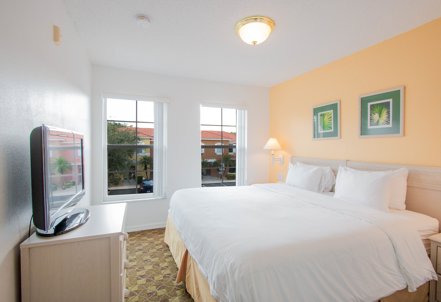 A wide view of a hotel room with a double bed, TV, and window